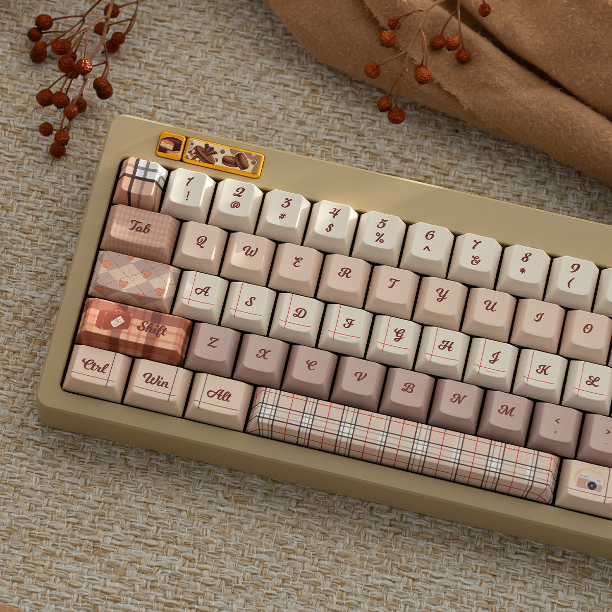 Close-up of a beige and pink autumn British style keycap set with plaid and heart patterns, featuring Cherry profile PBT material on a textured surface.