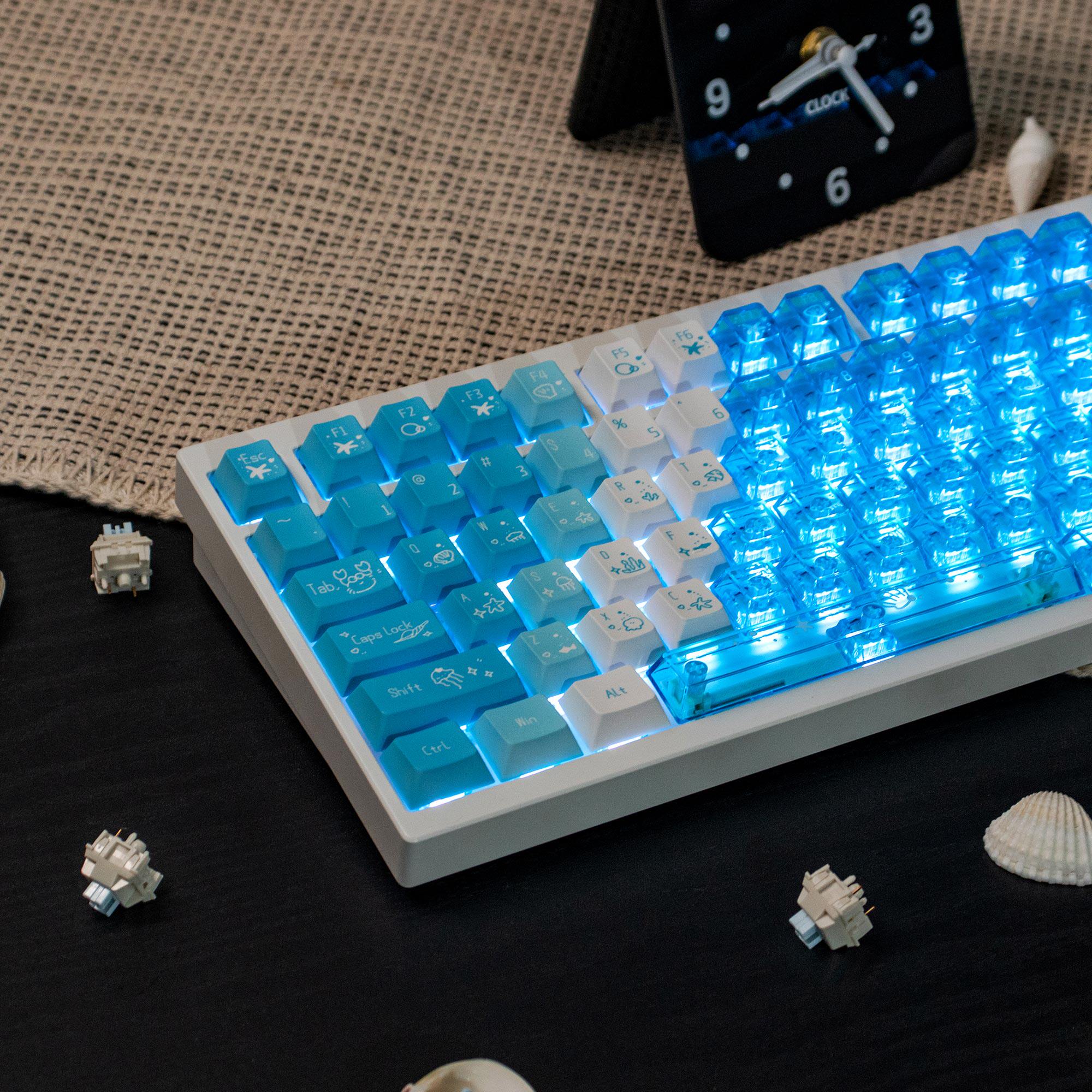 Angled view of custom Cherry profile Deep Sea Blue keyboard with a transparent blue chassis and backlight by Taptempo, high-value setup shipping to US and EU.