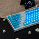 Angled view of custom Cherry profile Deep Sea Blue keyboard with a transparent blue chassis and backlight by Taptempo, high-value setup shipping to US and EU.